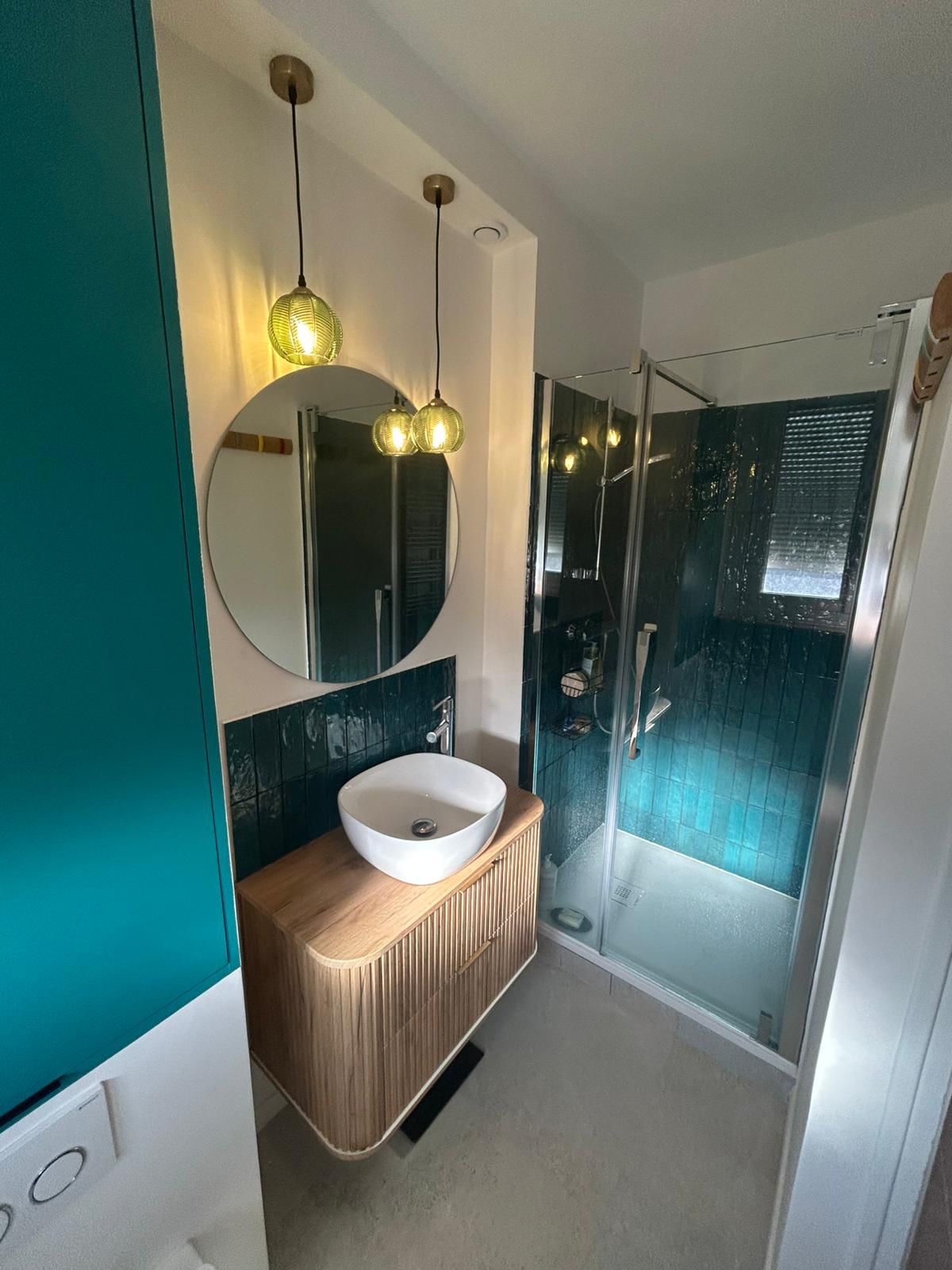 Salle de bain rénovée avec faïence vert profond, meuble bois et douche vitrée