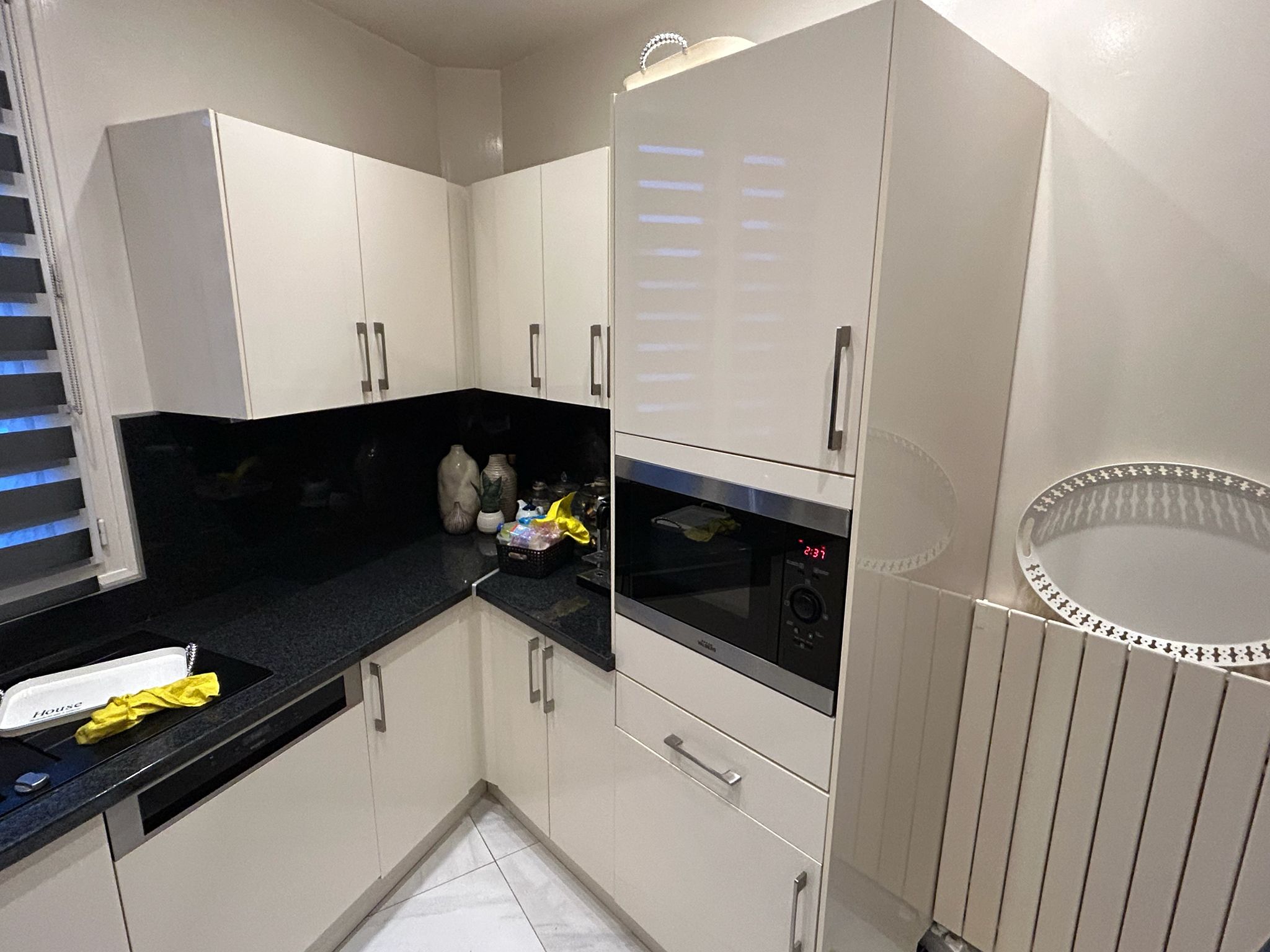 Cuisine avant rénovation avec colonne four, plan noir et façades ivoire