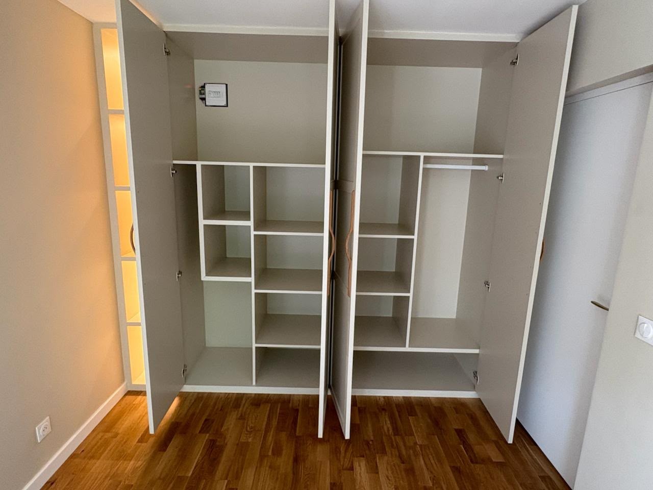 Dressing sur mesure finalisé ouvert avec rangements intérieurs, portes claires et éclairage chaud
